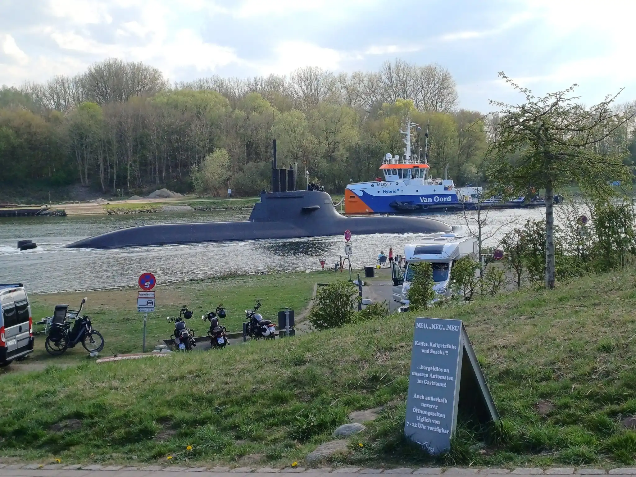 U-Boot und Van-Oord-Schiff auf dem Nord-Ostsee-Kanal bei Kiel, Motorräder und Wohnmobil am Ufer