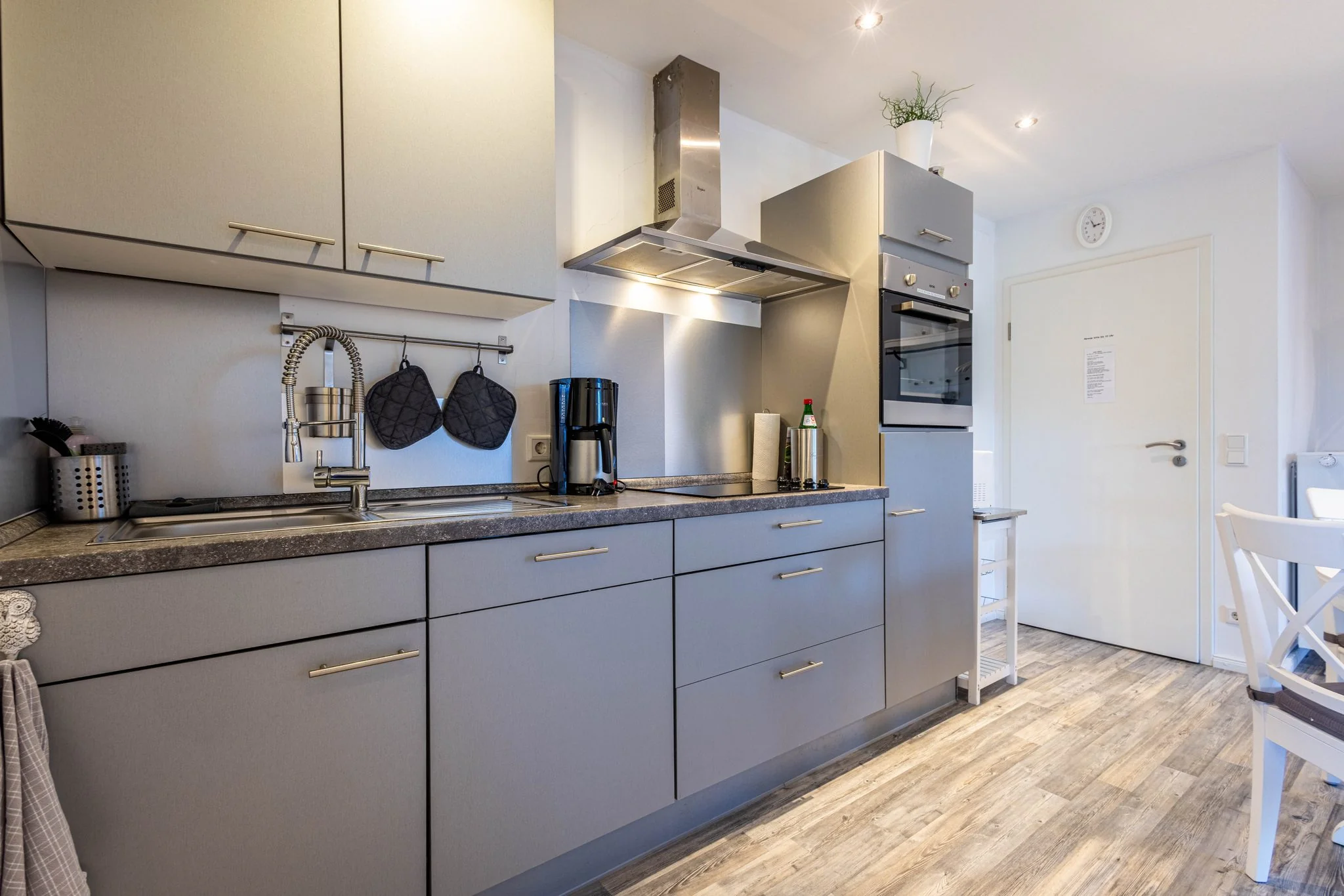 Moderne Ferienküche mit grauen Fronten, Induktionskochfeld, Dunstabzug und Kaffeemaschine