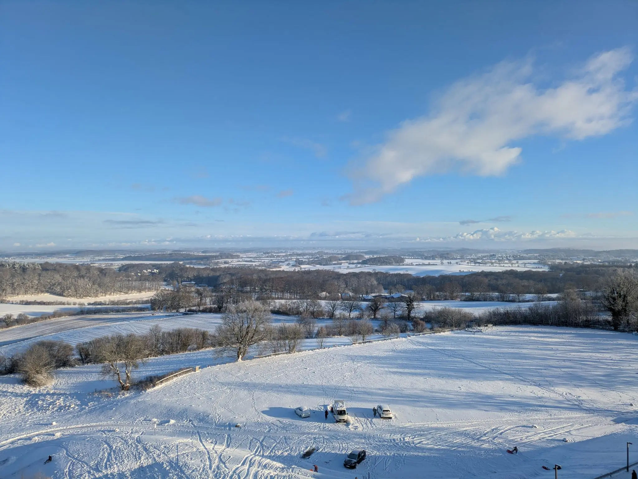 Verschneite Winterlandschaft mit weiten Feldern und blauem Himmel aus der Vogelperspektive